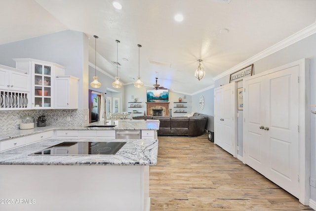 kitchen with black electric cooktop, a sink, a peninsula, lofted ceiling, and a fireplace