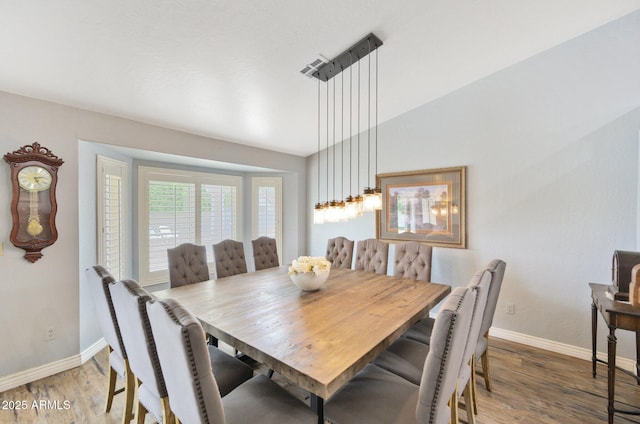 dining area featuring baseboards, light wood-style flooring, and lofted ceiling