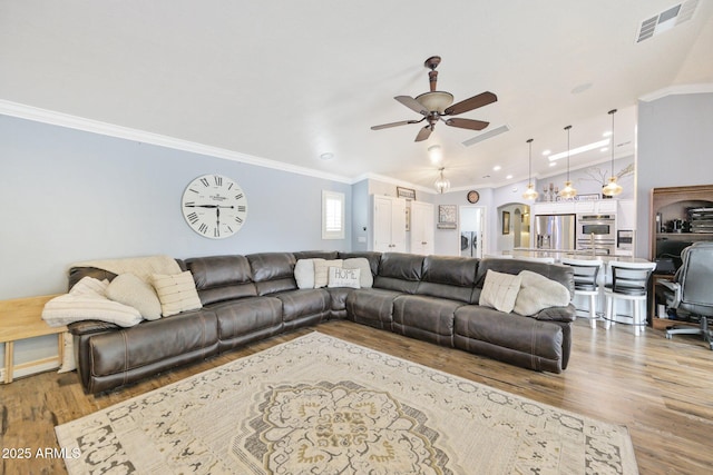 living area featuring wood finished floors, a ceiling fan, crown molding, and recessed lighting