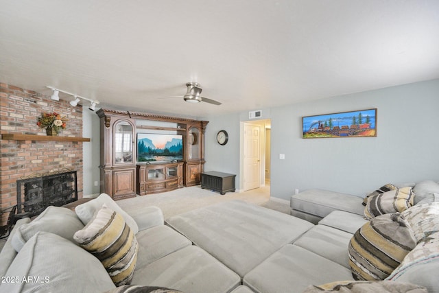 living room featuring ceiling fan, light carpet, a brick fireplace, and baseboards