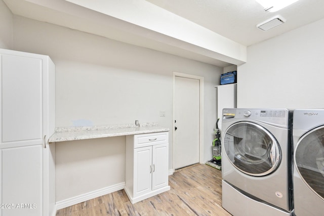 laundry room with light wood-style flooring, separate washer and dryer, and baseboards