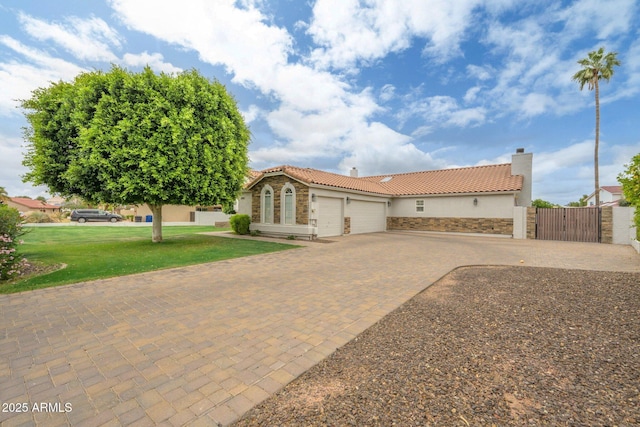 mediterranean / spanish-style house with a tiled roof, stone siding, and an attached garage