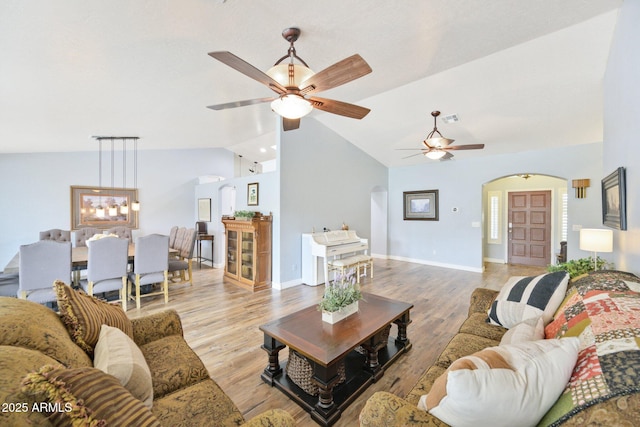 living room with arched walkways, lofted ceiling, a ceiling fan, light wood-style flooring, and baseboards