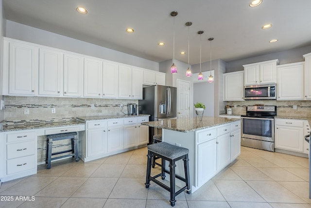 kitchen featuring hanging light fixtures, white cabinets, light tile patterned flooring, a center island, and stainless steel appliances