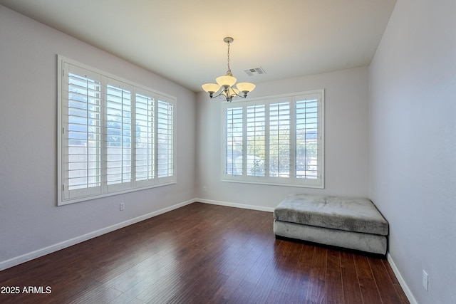 unfurnished room featuring dark wood-type flooring and a notable chandelier