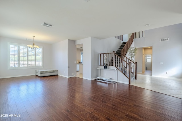 unfurnished living room featuring wood-type flooring and an inviting chandelier