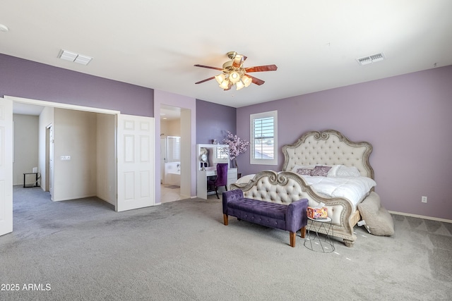 bedroom with ceiling fan, light colored carpet, and ensuite bath