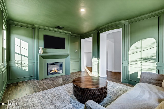 living area featuring a decorative wall, a lit fireplace, and wood finished floors