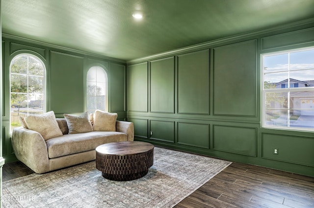 living area featuring a decorative wall and dark wood-style floors