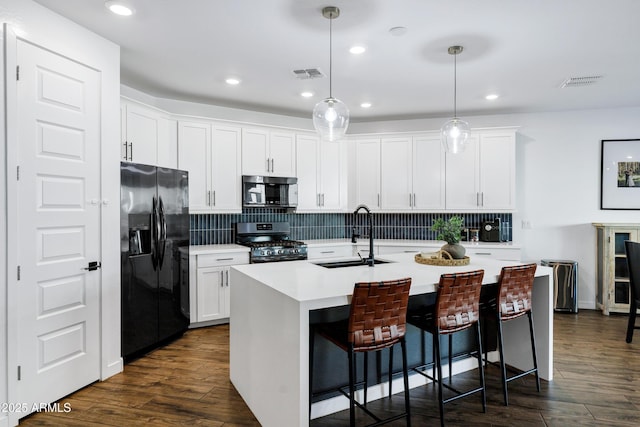 kitchen featuring black refrigerator with ice dispenser, a sink, gas range, stainless steel microwave, and tasteful backsplash