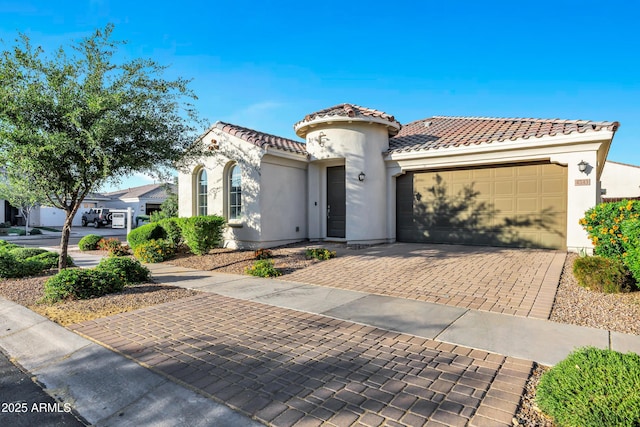 mediterranean / spanish-style house featuring a garage, decorative driveway, a tile roof, and stucco siding
