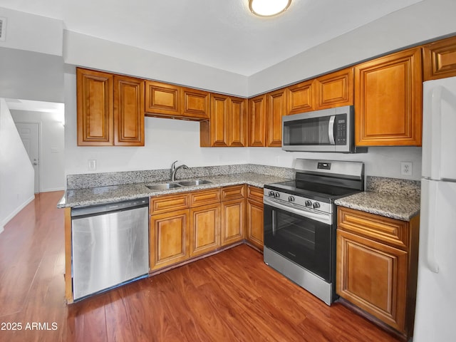1750 E Mateo Cir Unit 103, Mesa, AZ 85204 - kitchen featuring stainless steel appliances, dark wood-type flooring, brown cabinetry, and light stone counters
