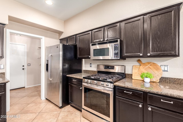 kitchen with stone counters, appliances with stainless steel finishes, dark brown cabinets, and light tile patterned floors