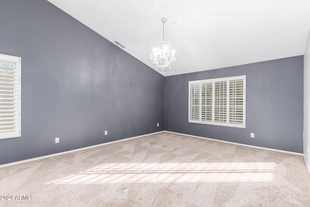 carpeted spare room featuring high vaulted ceiling and an inviting chandelier