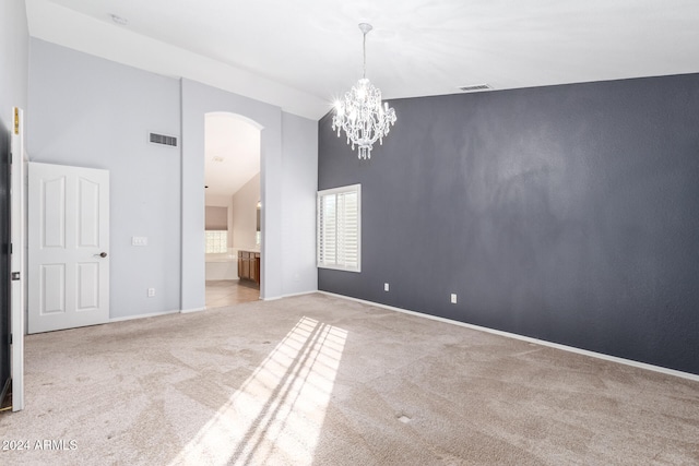 unfurnished room featuring a high ceiling, a chandelier, and light carpet