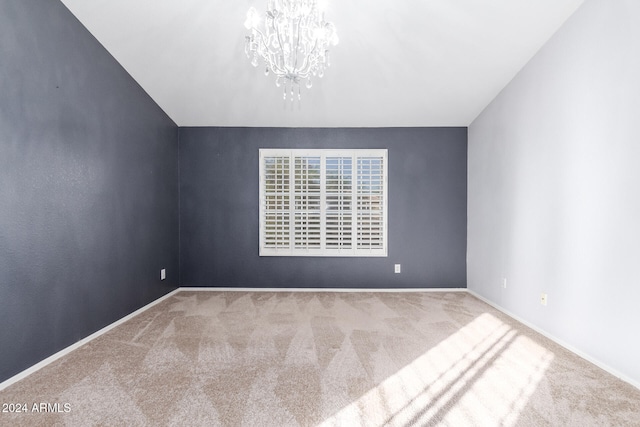 carpeted spare room featuring a notable chandelier