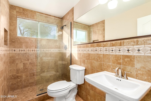 bathroom featuring sink, tiled shower, tile walls, and toilet