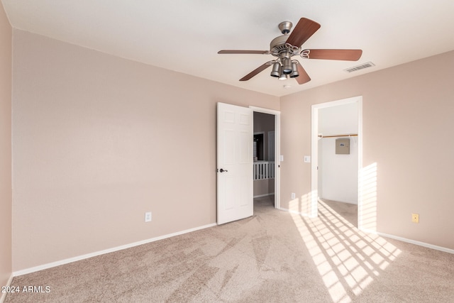 unfurnished bedroom featuring a spacious closet, light carpet, and ceiling fan