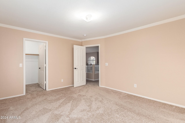 unfurnished bedroom featuring crown molding, a spacious closet, light colored carpet, and a closet