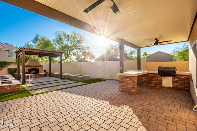 view of patio with exterior fireplace, ceiling fan, area for grilling, and a gazebo