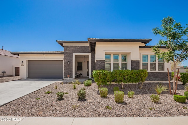 prairie-style home featuring stone siding, a garage, driveway, and stucco siding