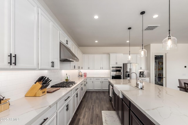kitchen with stainless steel appliances, white cabinets, dark wood-type flooring, tasteful backsplash, and pendant lighting