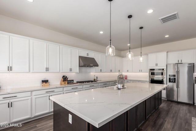 kitchen with stainless steel appliances, under cabinet range hood, a sink, white cabinets, and recessed lighting