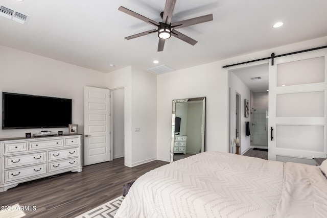 bedroom with dark wood-style floors, recessed lighting, a barn door, baseboards, and ensuite bath