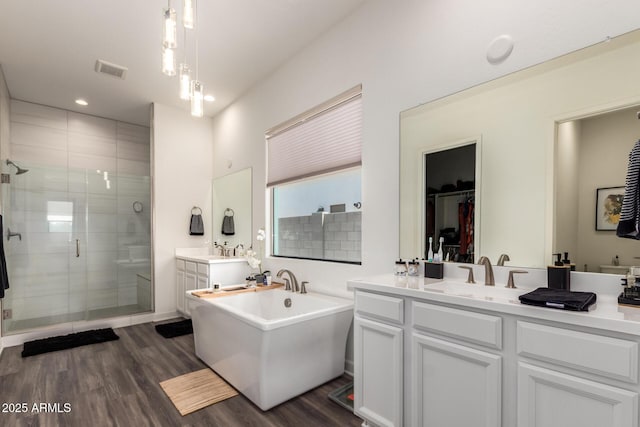 full bathroom with a shower stall, wood finished floors, a soaking tub, vanity, and recessed lighting