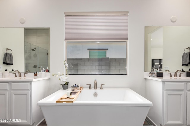 bathroom with a stall shower, two vanities, and a freestanding bath