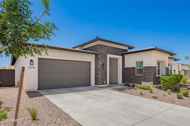 view of front of property with an attached garage, concrete driveway, stucco siding, brick siding, and fence