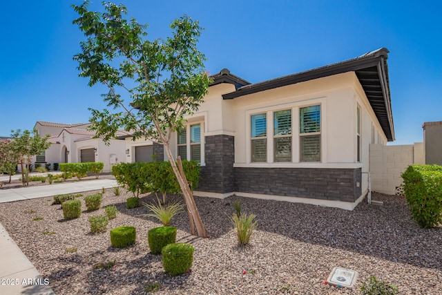 view of front of house with stone siding, stucco siding, an attached garage, and driveway