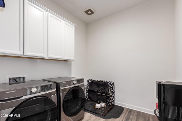 washroom with cabinet space, washer and dryer, wood finished floors, and baseboards