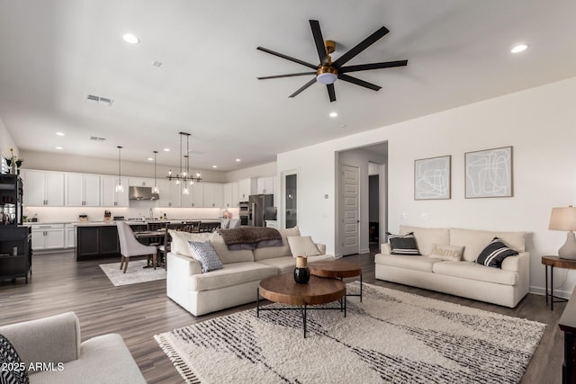 living room featuring ceiling fan, dark wood-style floors, recessed lighting, and a chandelier
