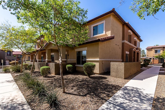 view of front facade with a tiled roof, a fenced front yard, and stucco siding