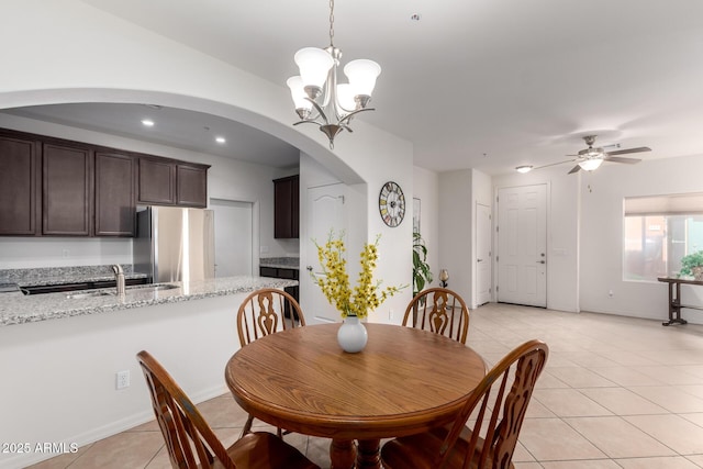 dining space with light tile patterned floors, recessed lighting, arched walkways, and ceiling fan with notable chandelier