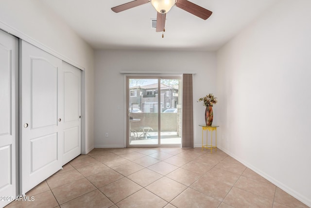 unfurnished bedroom featuring access to outside, light tile patterned flooring, baseboards, and a closet