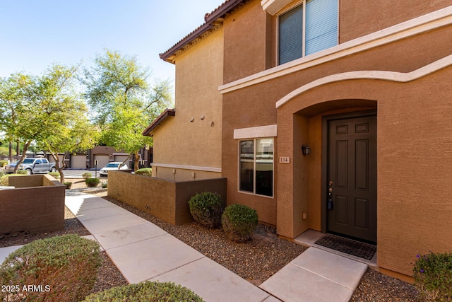 property entrance with stucco siding and a tile roof