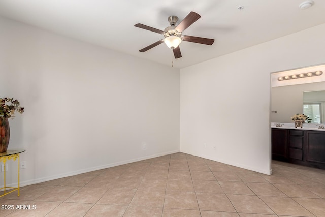 unfurnished room with light tile patterned floors, a ceiling fan, and baseboards