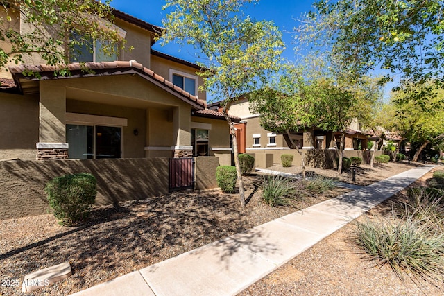 mediterranean / spanish-style home with a tile roof, a gate, a fenced front yard, and stucco siding