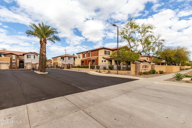 view of road with street lighting, a gated entry, a residential view, sidewalks, and a gate