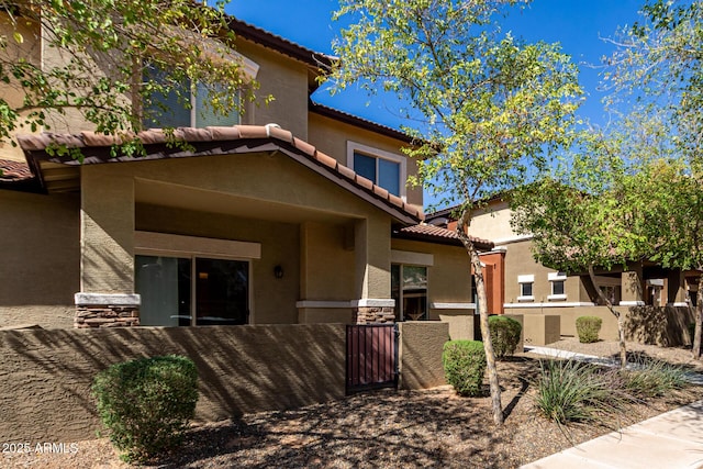 mediterranean / spanish house featuring a tile roof, fence, and stucco siding