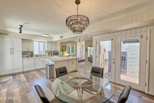 dining area featuring an inviting chandelier, sink, light hardwood / wood-style flooring, and french doors