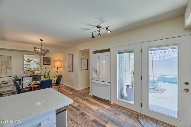 kitchen featuring white cabinetry, dark hardwood / wood-style flooring, light stone countertops, pendant lighting, and white refrigerator with ice dispenser