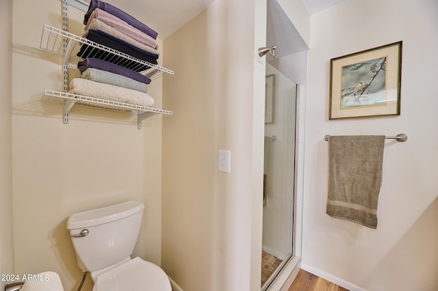 bathroom with hardwood / wood-style flooring, toilet, and walk in shower