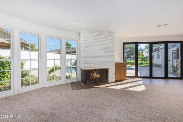 unfurnished living room featuring carpet floors and a stone fireplace