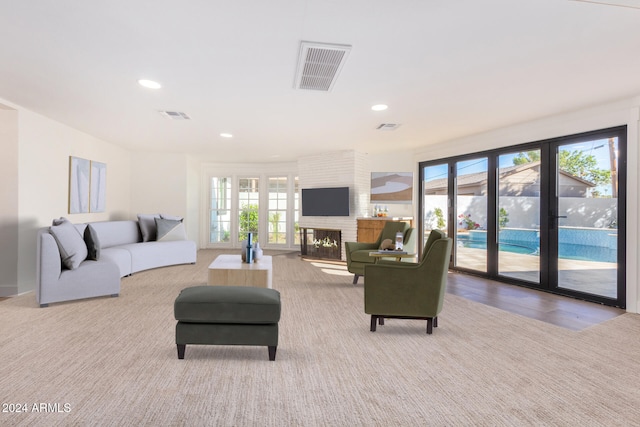 carpeted living room featuring a healthy amount of sunlight and a brick fireplace