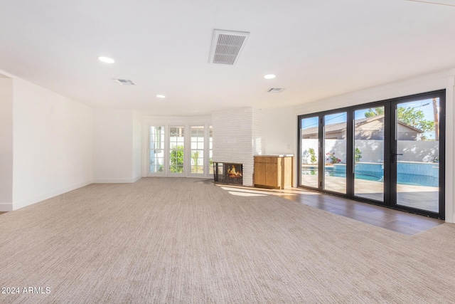 unfurnished living room with carpet and a brick fireplace