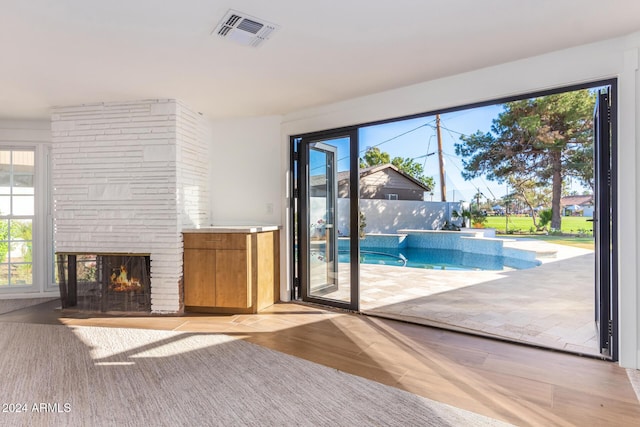 unfurnished living room featuring a stone fireplace, light wood-type flooring, and a wealth of natural light