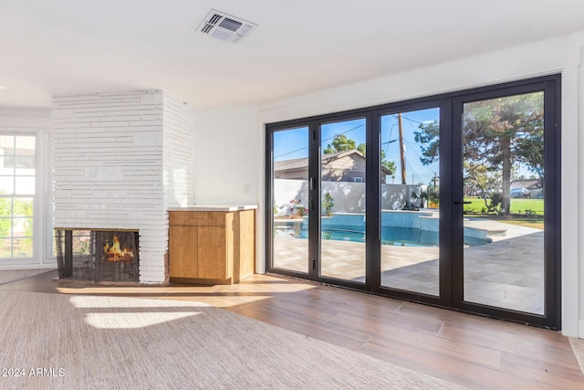 unfurnished living room featuring a healthy amount of sunlight, wood-type flooring, a fireplace, and french doors